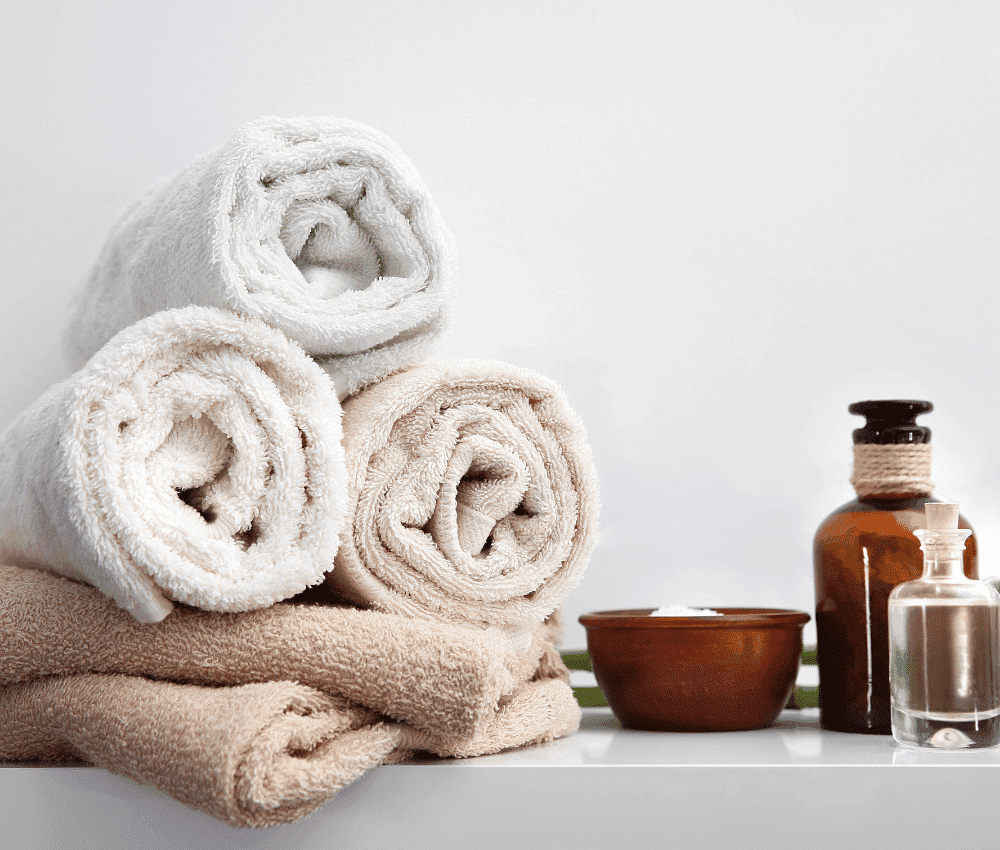 Rolled towels with toiletries on a white background.