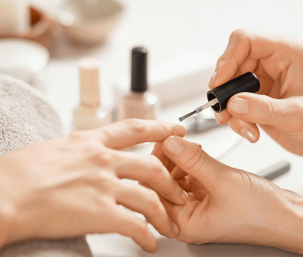Person applying nail polish on fingernails, manicure process.