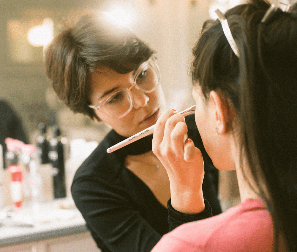 Makeup artist applying eyeliner to a client.